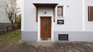 Ein modernes Gebäude mit einer Holztür, einem kleinen Fenster und einem Schild mit der Aufschrift 'Flute'.