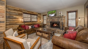 A cozy living room with a stone fireplace, wooden walls, and a comfortable seating area. - Southern Luxury (Sevierville)