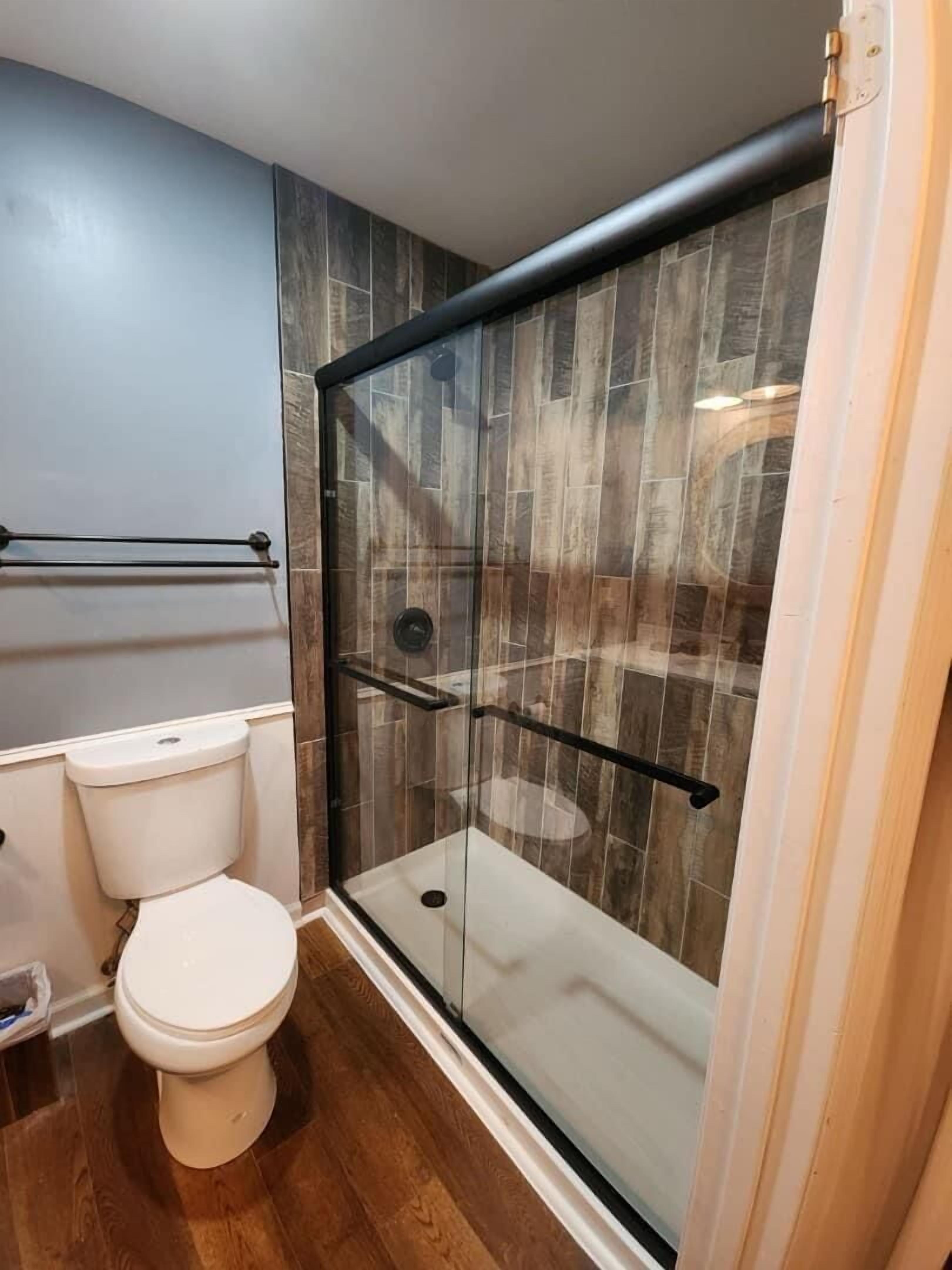 Ein Badezimmer mit einer gläsernen Duschkabine, einer Toilette und einem Handtuchhalter.
