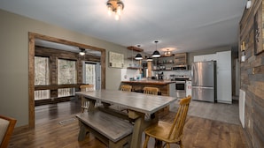 A spacious kitchen with wooden flooring, a large dining table, and modern appliances. - Southern Luxury (Sevierville)