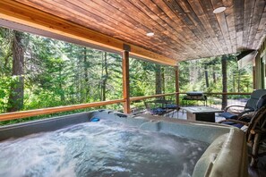 A hot tub with a wooden ceiling and a view of a forest.