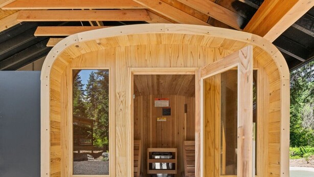 A wooden cabin with a single door open, revealing a small kitchenette and a window.