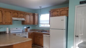 A kitchen with wooden cabinets, a white refrigerator, a stove, and a sink.