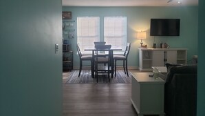 A compact living space with a dining area, a TV mounted on the wall, and a ceiling fan.
