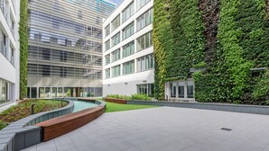 A modern building with a rooftop garden, a swimming pool, and a green wall.