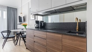 A modern kitchen with dark wood cabinets, a black countertop, and a stainless steel range hood.
