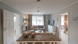 Uma sala de estar moderna com uma mesa de jantar de madeira, um sofá e uma televisão.