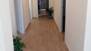 A hallway with wooden flooring, white walls, and doors leading to other rooms. There are potted plants along the sides. - Bright Apartment with Terrace Cin Code IT092080C2000Q2483 (Sinnai)