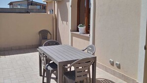 A patio with a table and chairs, a potted plant, and a wall-mounted air conditioning unit. - Bright Apartment with Terrace Cin Code IT092080C2000Q2483 (Sinnai)