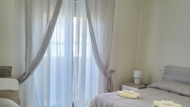 A hotel room with two beds, a bedside table with a lamp, and sheer curtains. - Bright Apartment with Terrace Cin Code IT092080C2000Q2483 (Sinnai)