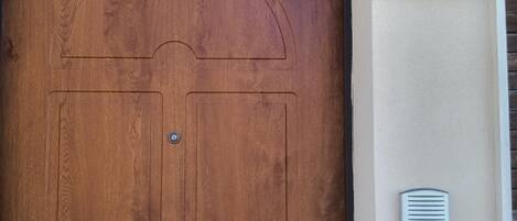 A wooden door with a brass doorknob, a mailbox, and a wall-mounted intercom.