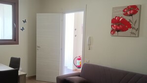 A living room with a brown sofa, a dining table with chairs, a white door, and a wall-mounted painting of red flowers. - Bright Apartment with Terrace Cin Code IT092080C2000Q2483 (Sinnai)