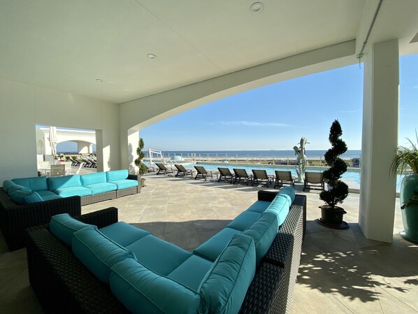 Un espace extérieur aménagé, abrité et doté de fauteuils et de canapés confortables, ainsi qu’une piscine et une vue sur l’océan.