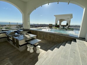 A rooftop pool area with a bar and seating, overlooking a cityscape. - Emerald #701 Luxury 3BR/2.5BA w/Huge Wraparound Balcony, Pool & Hot Tub (Galveston)