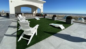 Terraza en la azotea con sillones blancos, una pequeña barra y vistas al océano.