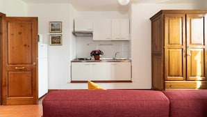 Una cucina compatta con mobili bianchi, una porta in legno e una ventola a soffitto.