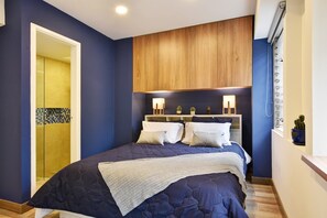 A bedroom with a bed, bedside tables, a wooden headboard, and a window with a view. - Homey Atmosphere 3BR Flat steps from Provenza with A/C (Medellín)