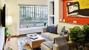 Ein Wohnzimmer mit einer Couch, einem Couchtisch und einem großen Fenster mit Blick auf Bäume.