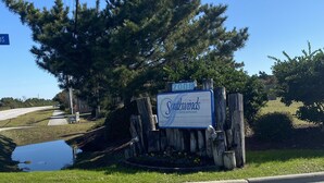 A sign for Southwinds Condominiums with a clear sky and a large tree in the background. - Atlantic Beach Condo within walking distance to the beach (Atlantic Beach)