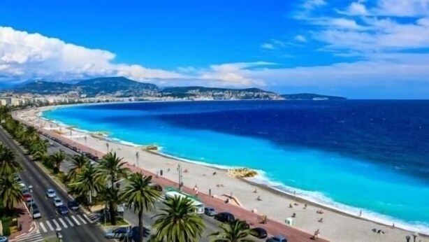 A coastal road with a beach, palm trees, and a clear blue sea. - Villa Avec Piscine Chauffée Nice Collines (Nice)