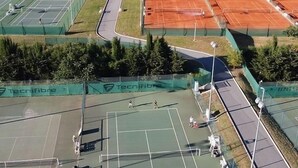 An aerial view of a sports complex with multiple tennis courts, a covered area, and a large building with a flat roof. - Villa Avec Piscine Chauffée Nice Collines (Nice)