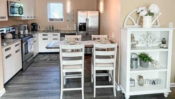 Una cocina moderna con armarios blancos, una isla central e iluminación colgante.