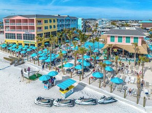 Ein Strandhotel mit mehreren Balkonen, einem Poolbereich und einem Parrot Parrot Restaurant.