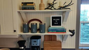 A kitchen with a coffee maker, a Cuisinart espresso machine, and a coffee grinder on the counter.