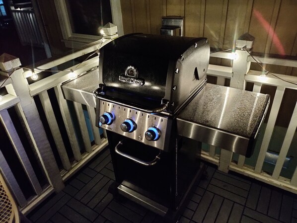 A portable gas grill with a digital display and four control knobs, situated on a wooden deck with a white railing. - Modern 3 Bedroom, 2 Bath Condo w/ pool near village (The Blue Mountains)