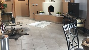 Un salón acogedor con chimenea, techo de madera y varias obras de arte.