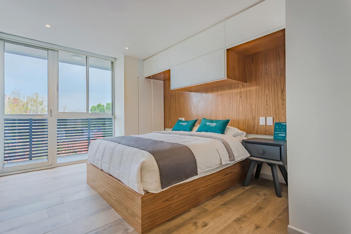 Een moderne slaapkamer met een houten bed, een bureau en een groot raam.