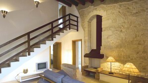 Un saló modern amb escala, paret de pedra i llar de foc.