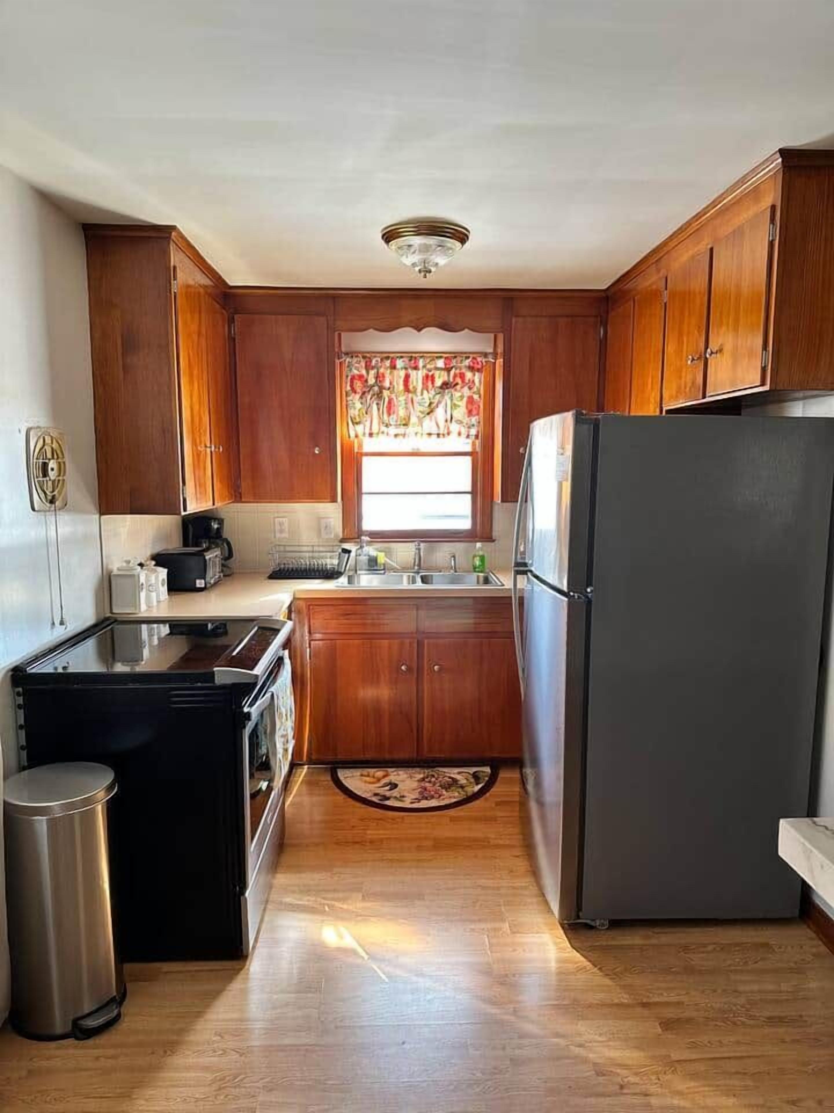 Una cocina compacta con armarios de madera, un refrigerador, una estufa y un lavaplatos.