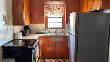 Una cocina compacta con armarios de madera, un refrigerador, una estufa y un lavaplatos.