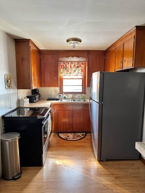 A compact kitchen with wooden cabinets, a refrigerator, a stove, and a sink. - Free Parking/ Wifi/ Family Home 2 Min to the Falls (Niagara Falls)