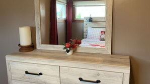 A wooden dresser with a mirror, drawers, and a candle.