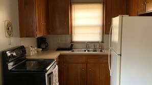 A kitchen with wooden cabinets, a white refrigerator, a stove, and a sink.