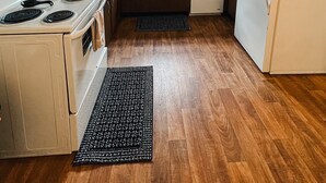Une cuisine de taille réduite, avec des meubles en bois, une cuisinière blanche, un évier et un réfrigérateur.