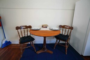 Une table à manger avec deux chaises, un balai et une petite boîte posée sur la table.
