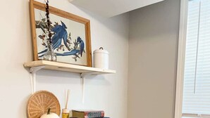 Ein Zimmer mit Bücherregal, einem gerahmten Kunstwerk und einem Fenster.