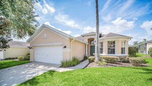A two-story house with a garage, a covered porch, and a well-maintained lawn.