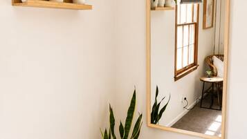 A room with a large mirror, a potted plant, and a bed with floral bedding.