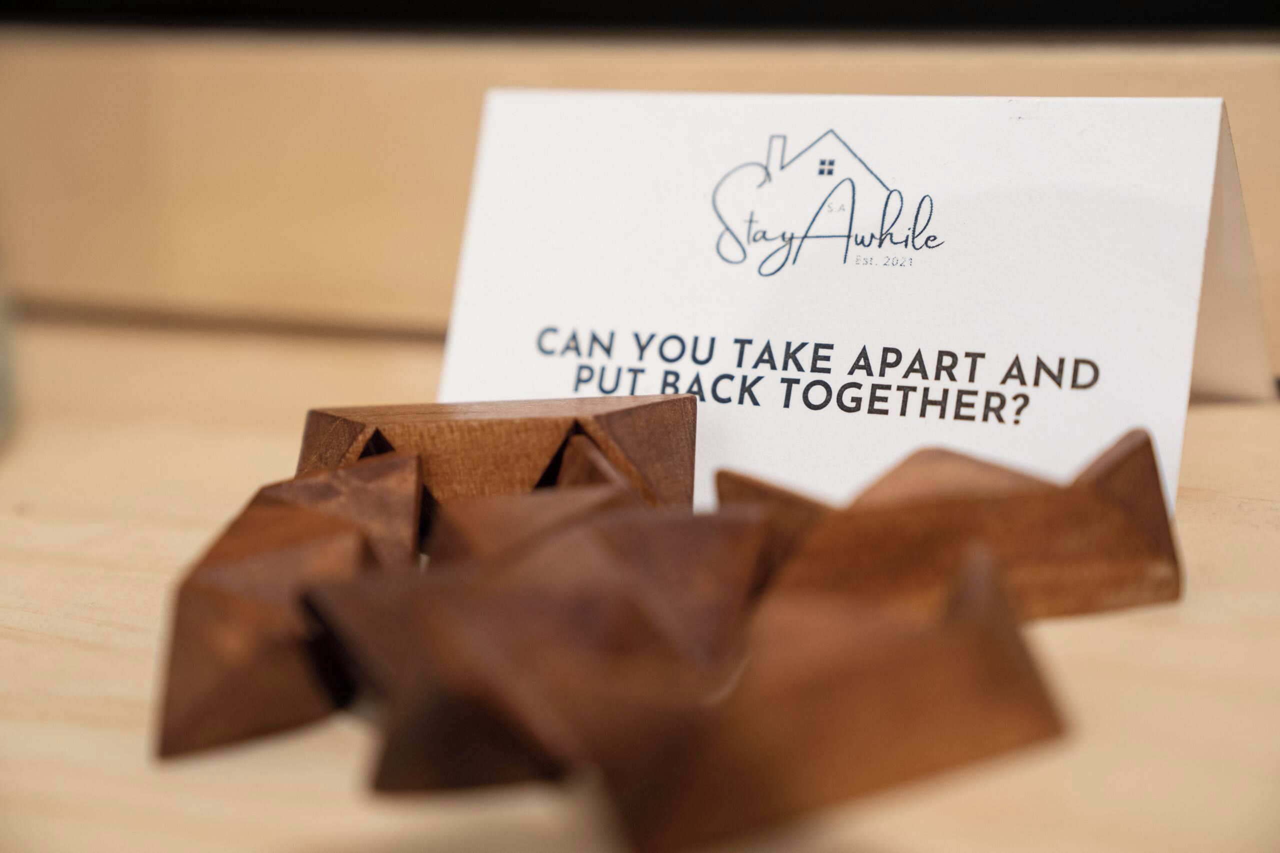 Une carte avec le logo d’une maison et le texte « Restez éveillé » ainsi qu’une question : « Pouvez-vous démonter et remonter ? », avec des pièces de puzzle en bois devant.