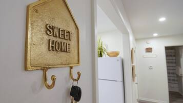 A wall-mounted key holder with a house-shaped sign that reads 'SWEET HOME' and a set of keys hanging from it.