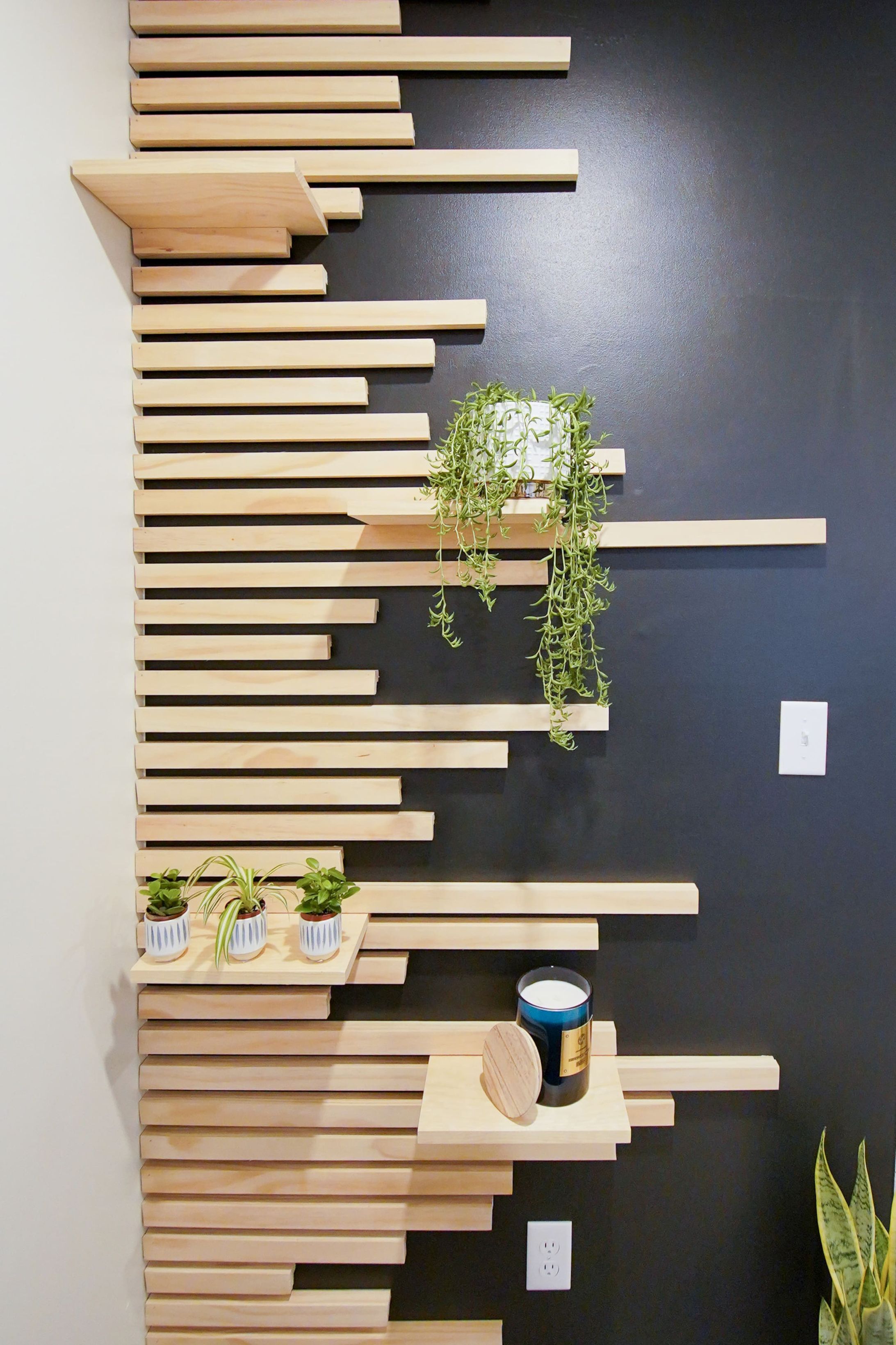 Un mur orné de plusieurs étagères horizontales en bois, de différentes longueurs.