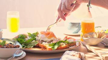 Una escena de desayuno con diversos alimentos sobre una mesa, incluyendo tostadas, un bol de papas fritas y un vaso de jugo de naranja.