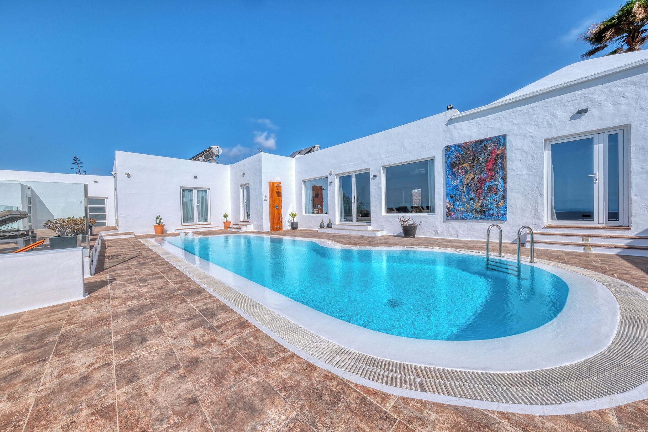 Un'area piscina moderna con vasca azzurra, pareti bianche e pavimento piastrellato.