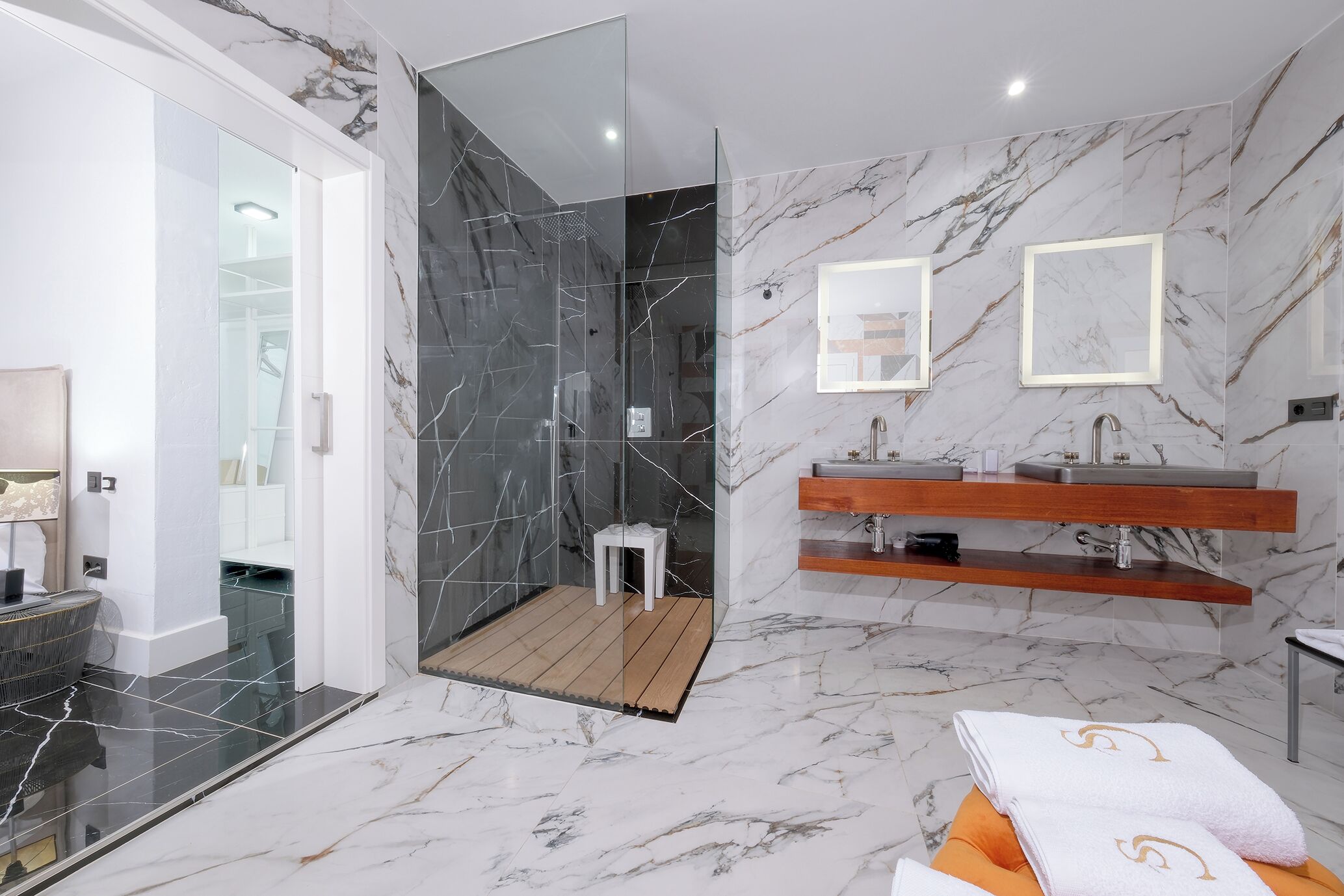 Un baño moderno con ducha de vidrio, suelo de mármol y tocador de madera.
