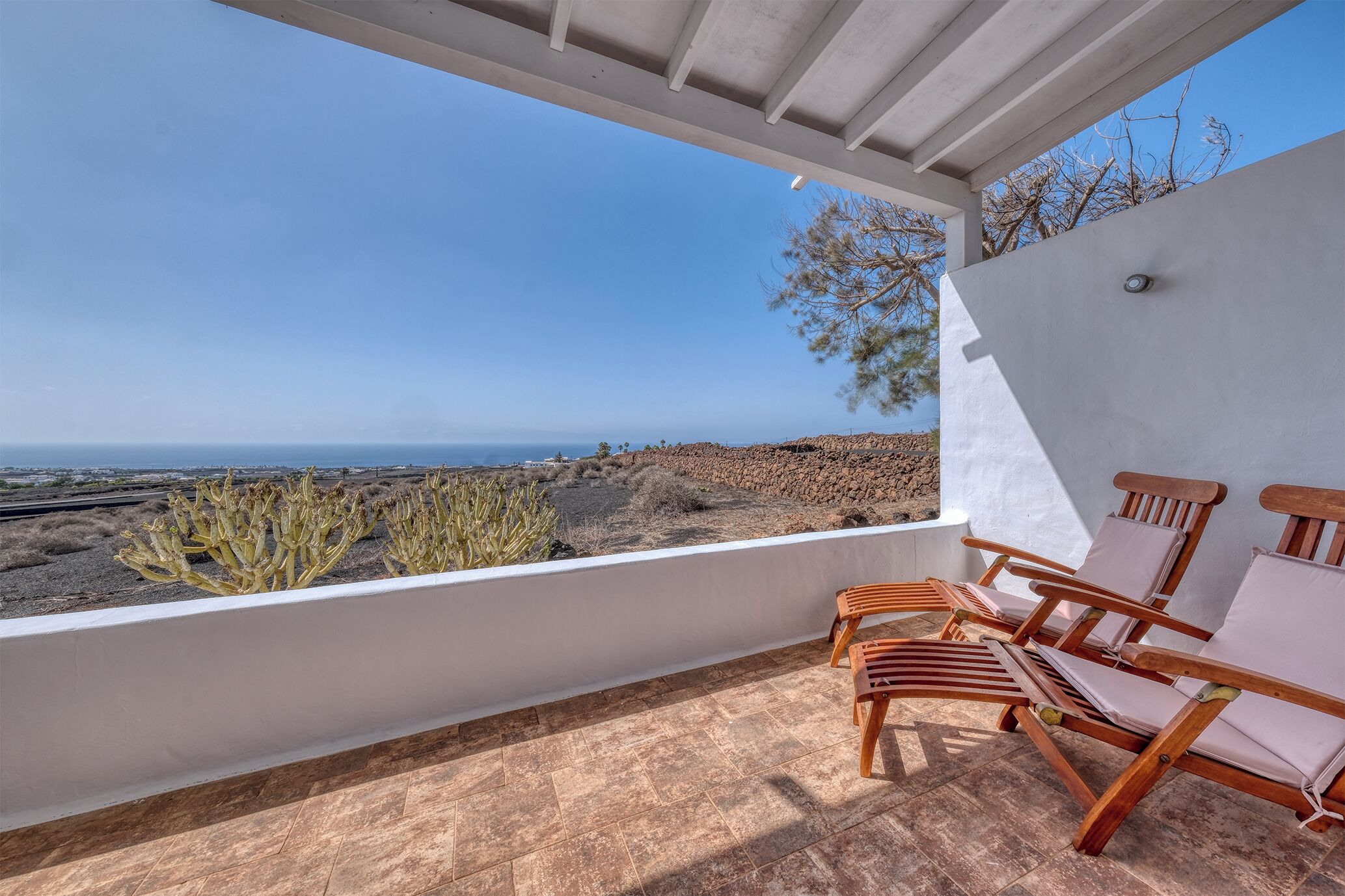 Un balcon avec des chaises en bois et une vue sur le paysage désertique.