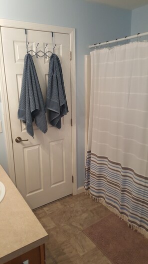 Bañera con ducha, toallas, jabón, papel higiénico